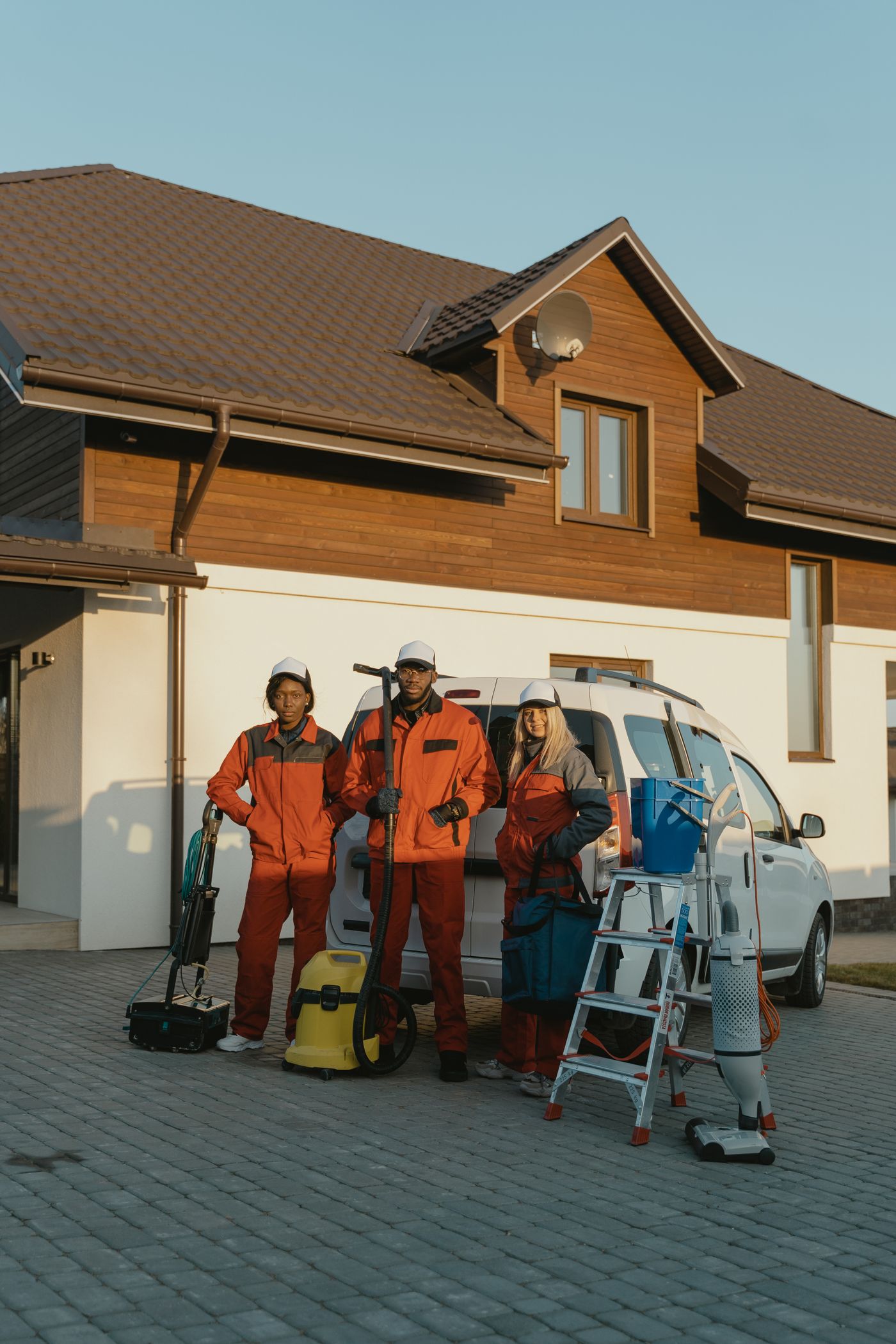 Home service crew wearing work uniforms and carrying equipment outside a house